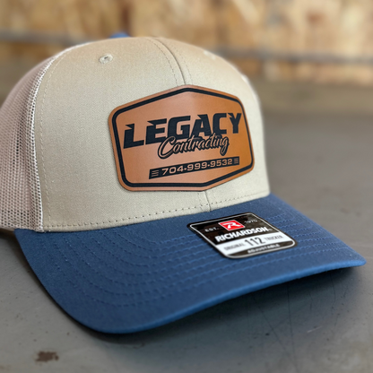 Beige and blue cap with 'Legacy Contracting' logo on a blurred background