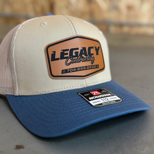 Beige and blue cap with 'Legacy Contracting' logo on a blurred background